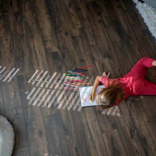 Girl drawing on hardwood floor in Grand Rapids, MI at Absolute Floor Covering